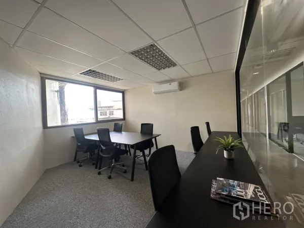 Office Space for rent in Bang Rak, Bangkok - Bright meeting room with desks, mesh chairs, large window, and wall-mounted air conditioner.