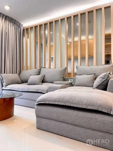 Condominium for rent - Close-up of a plush gray sectional sofa beside a slatted room divider.