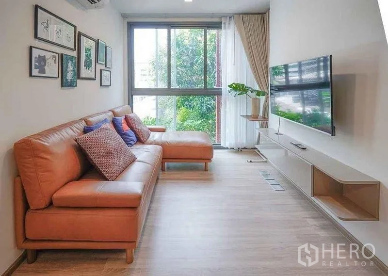 公寓 出租在Watthana, Bangkok - 舒适客厅，L型沙发、悬浮电视柜与落地窗。