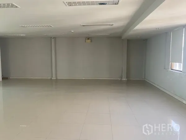 Office Space for rent in Bang Na, Bangkok - Wide empty workspace with light grey walls, ceiling lights and partial roller blinds.