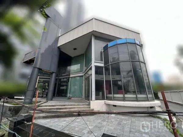 Retail Space for rent - Street-facing glass pavilion corner of the building with rounded bay window and entry steps.