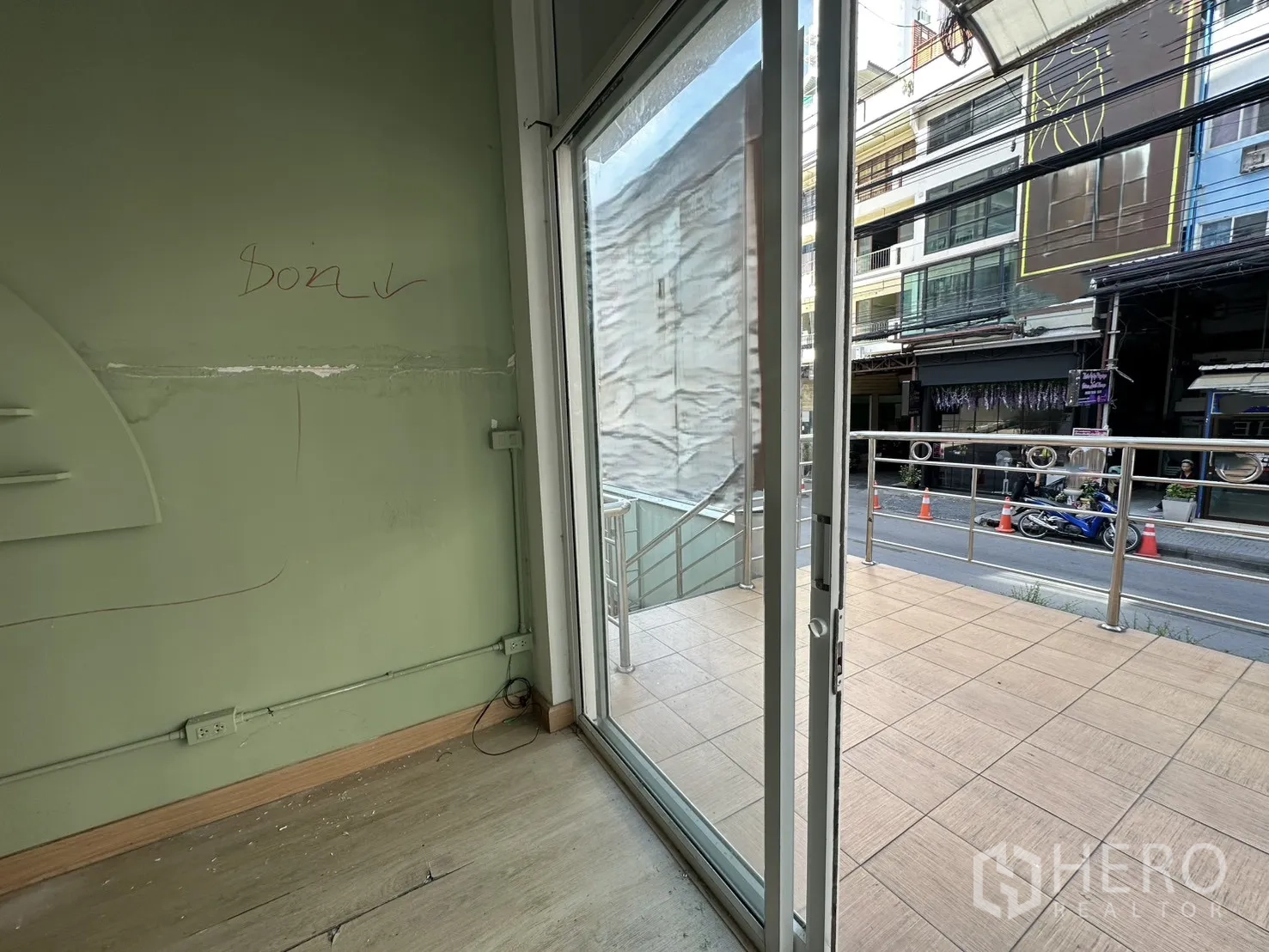 พื้นที่ขายของ for rent in Khlong Toei, Bangkok - ประตูกระจกบานเลื่อนเปิดสู่ระเบียงกระเบื้องขนาดเล็ก มองเห็นถนนด้านหน้า