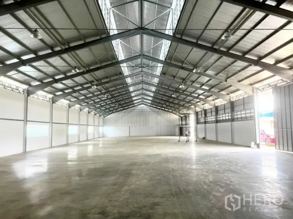 Warehouse for rent in Mueang Samut Prakan, Samut Prakan - Spacious warehouse interior with high steel truss roof and polished concrete floor.
