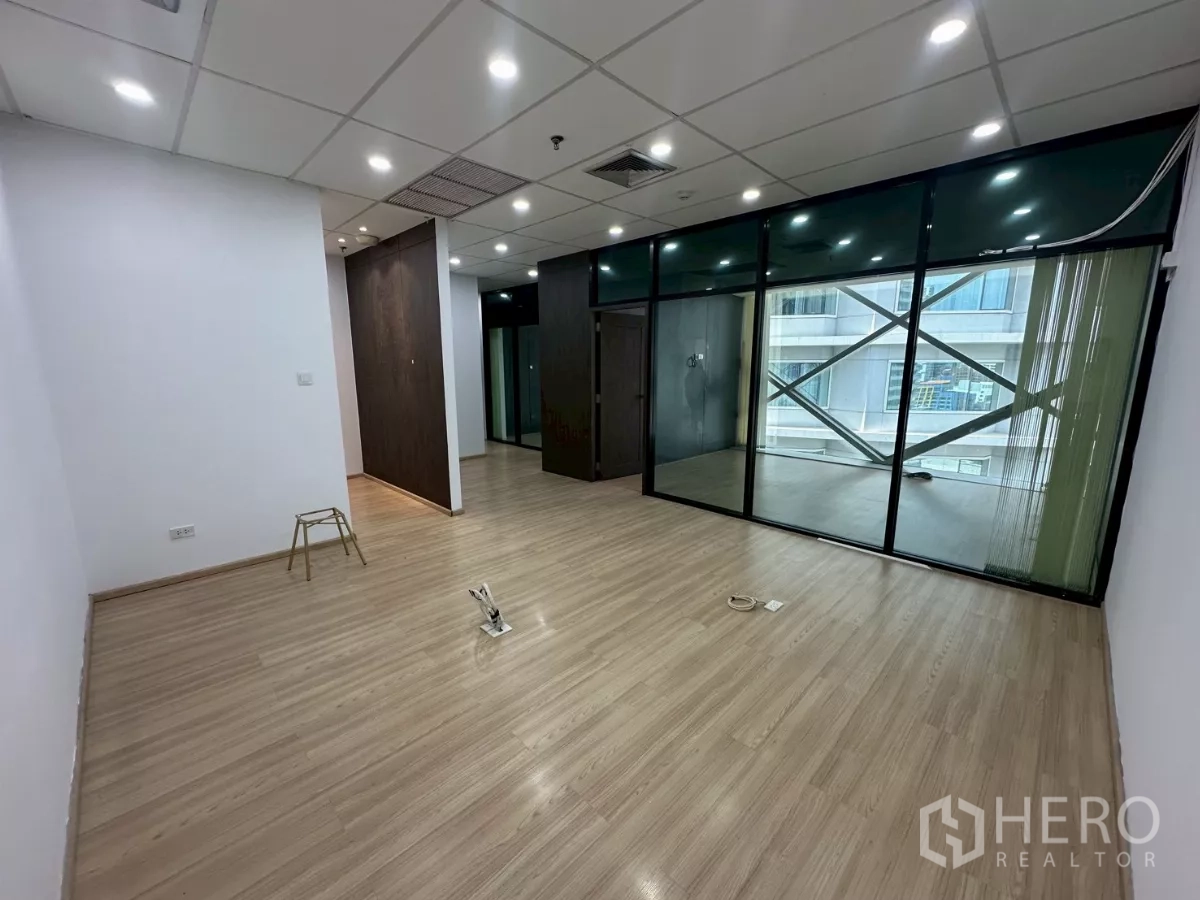 办公空间 出租在Watthana, Bangkok - 开放式办公区，木地板，整面玻璃隔断与射灯。