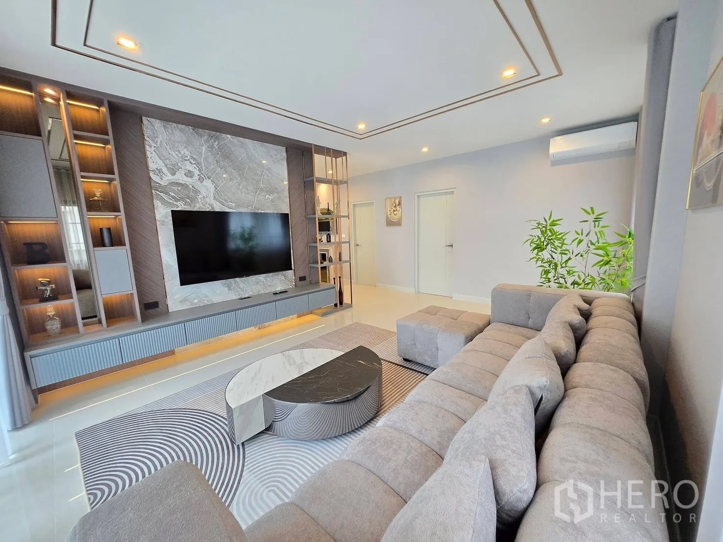 Detached House for rent in Bang Phli, Samut Prakan - Modern living room with a large sectional sofa and marble feature TV wall.