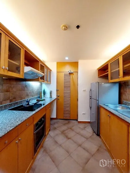 Apartment for rent - Galley kitchen with granite counters, cooktop, oven, range hood and stainless fridge.