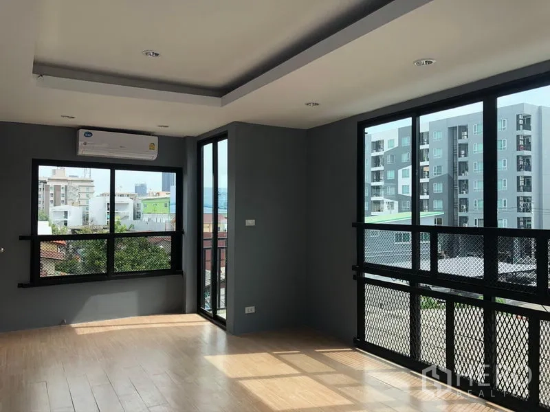 带办公室的家 出租在Suan Luang, Bangkok - 采光充足的转角办公区，落地窗与木纹地板，可眺望城市建筑。