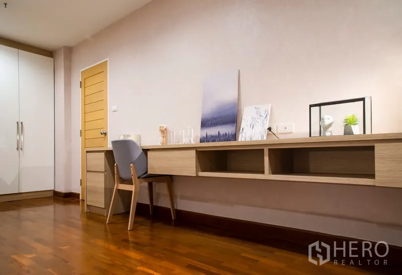 Condominium for rent in Pathum Wan, Bangkok - Bedroom corner with built-in work desk, storage and wood flooring.