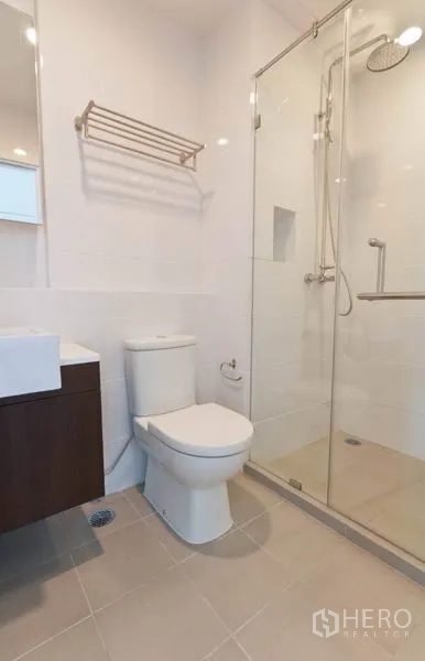 Condominium for rent in Phaya Thai, Bangkok - Contemporary bathroom with glass-enclosed shower, vanity and toilet in neutral tones.