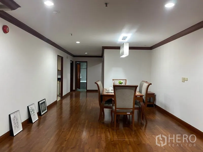 Condominium for rent in Watthana, Bangkok - Long dining hall with wood floors leading to rooms, framed artwork along the wall.