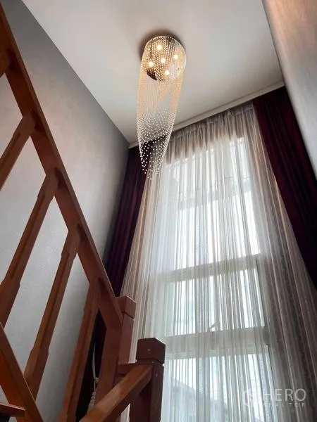 Detached House for sale in Bang Kruai, Nonthaburi - Staircase landing with tall window, sheer curtains, and a cascading chandelier.