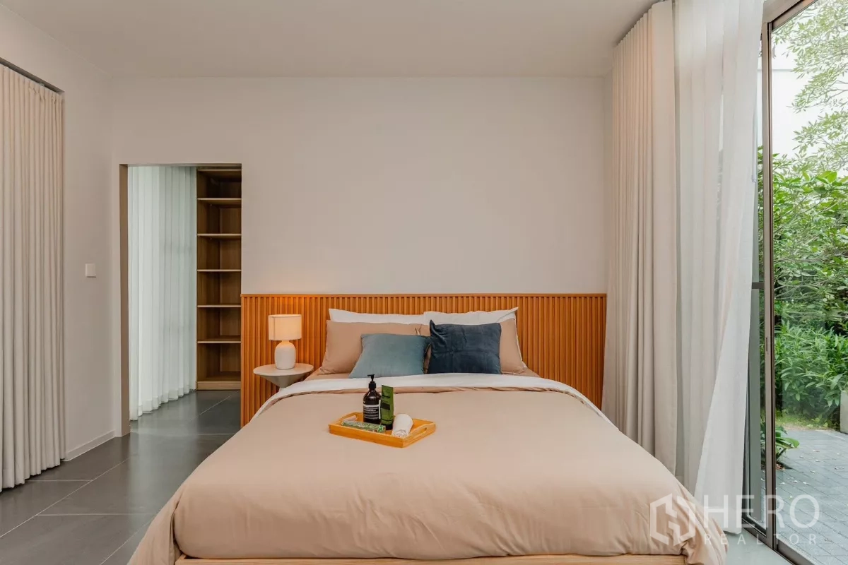 Detached House for rent in Saphan Sung, Bangkok - Cozy bedroom with warm wood headboard and walk-in closet entrance.
