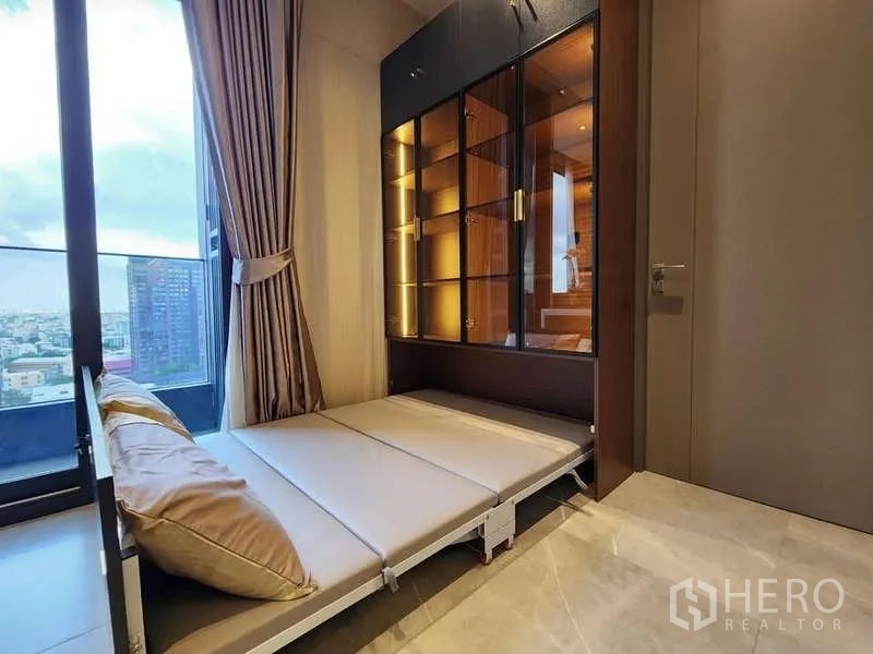 คอนโด ให้เช่าในWatthana, Bangkok - ห้องอเนกประสงค์พร้อมเตียงพับ ตู้โชว์กระจก และประตูออกสู่ระเบียง