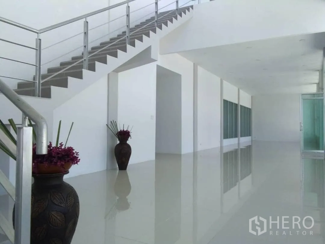 Factory for rent or sale in Bang Sao Thong, Samut Prakan - Staircase with stainless railing in white lobby and decorative vases.