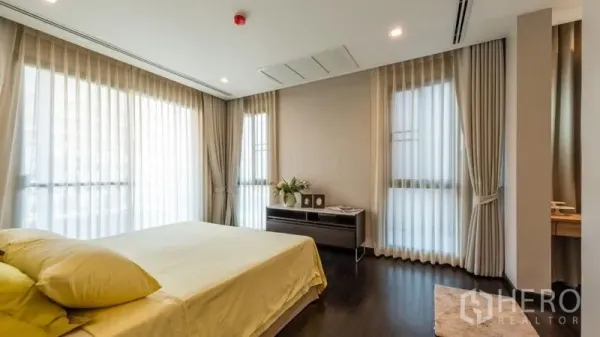 房间 出租在Pathum Wan, Bangkok - 主卧明亮，转角大窗与浅色窗帘，木地板与极简软装。