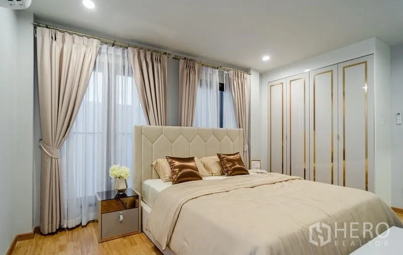 Detached House for sale in Lam Luk Ka, Pathum Thani - Master bedroom with upholstered headboard, built-in wardrobe, and wood flooring.
