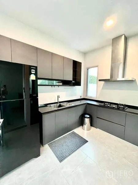 Detached House for rent or sale in Bang Phli, Samut Prakan - Sleek U-shaped kitchen with modern cabinets, gas hob, range hood and large fridge.