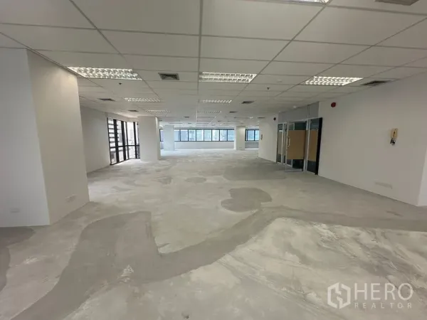 Office Space for rent in Bang Rak, Bangkok - Unfurnished office floor with grid ceiling, recessed lighting and glass entry doors.