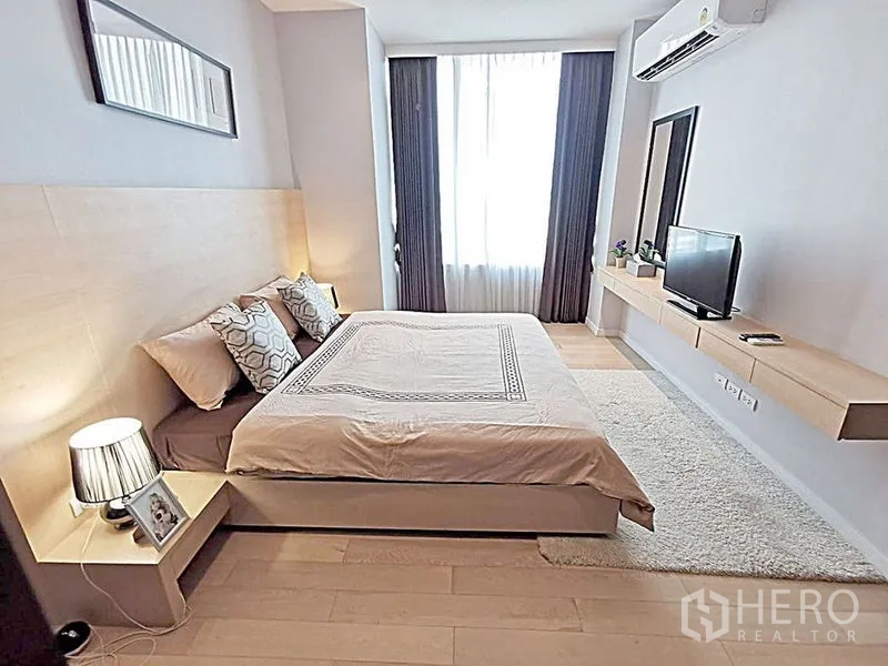 คอนโด ให้เช่าในWatthana, Bangkok - ห้องนอนกว้าง เตียงคิงไซส์ โคมไฟหัวเตียง ทีวีติดผนัง และหน้าต่างสูงพร้อมผ้าม่าน