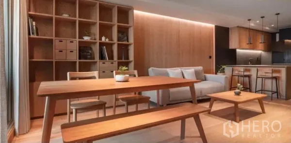 Condominium for rent in Phaya Thai, Bangkok - Dining area with wooden table, bench seating and open shelving beside the kitchen.