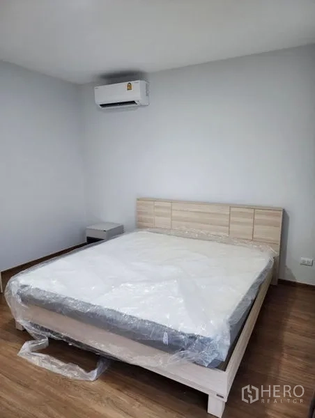 Townhouse for rent in Bang Phli, Samut Prakan - Minimalist bedroom with a queen bed, wood flooring, and wall-mounted air conditioner.