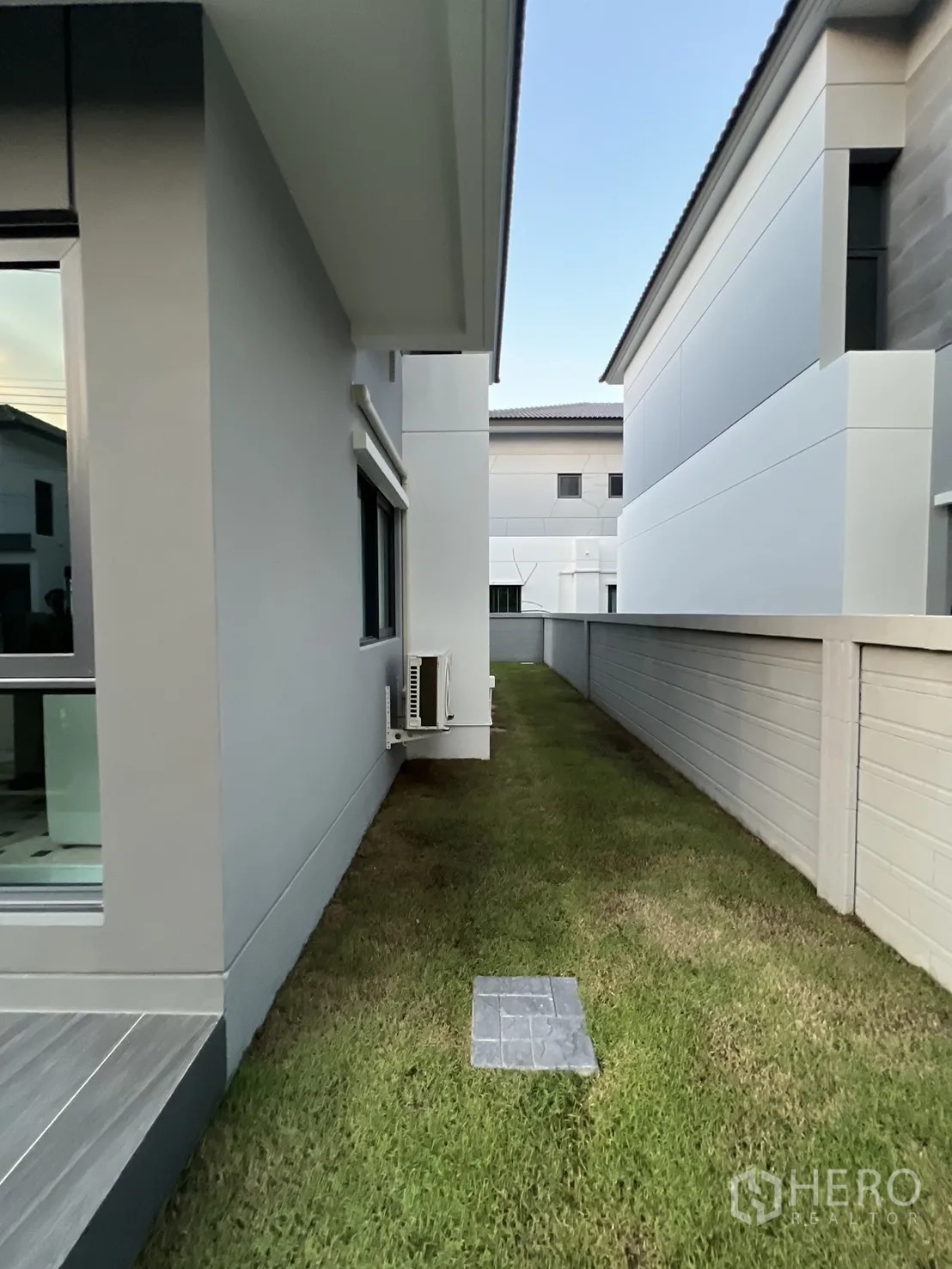Detached House for rent in Bang Phli, Samut Prakan - Side yard with narrow grass strip and privacy wall along the house.