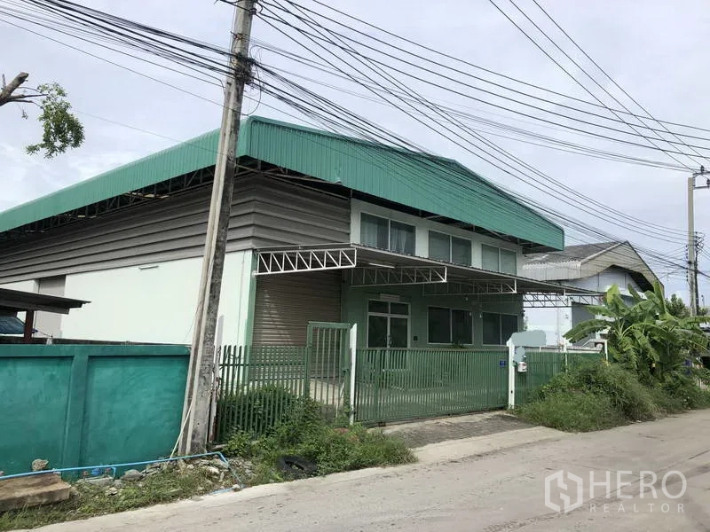 Factory for rent or sale in Samut Prakan - Standalone factory with green metal roof, roller shutter and gated entrance on a quiet industrial lane in Bang Phli.