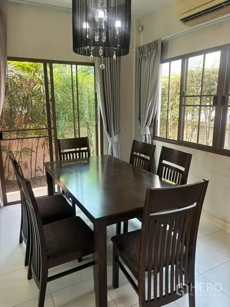独立式住宅 出租在Bang Phli, Samut Prakan - 餐厅摆放六人木餐桌，旁有窗户与推拉门