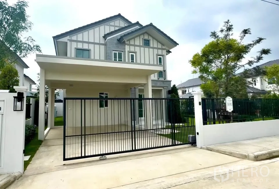 Detached House for rent in Bang Phli, Samut Prakan - Two-storey detached house exterior with gated driveway, covered carport, and landscaped lawn.