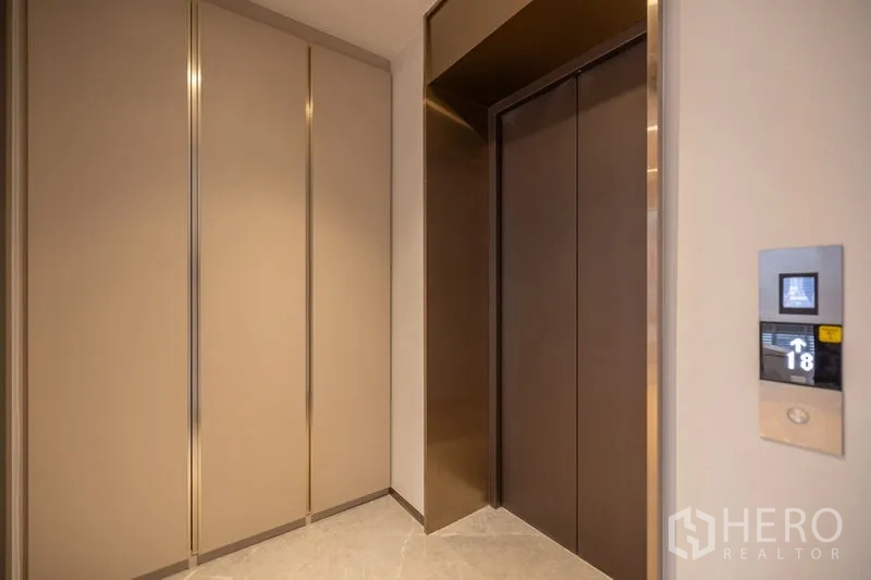 Condominium for rent in Pathum Wan, Bangkok - Private lift entry with built-in storage cabinets in warm neutral tones.