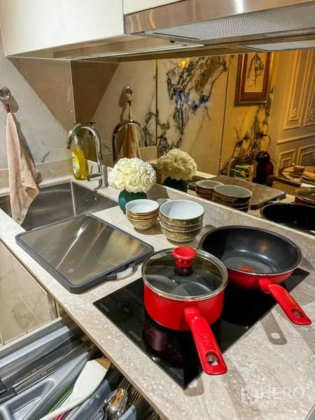 Condominium for rent - Compact kitchenette with marble backsplash, sink, and induction hob with red cookware.