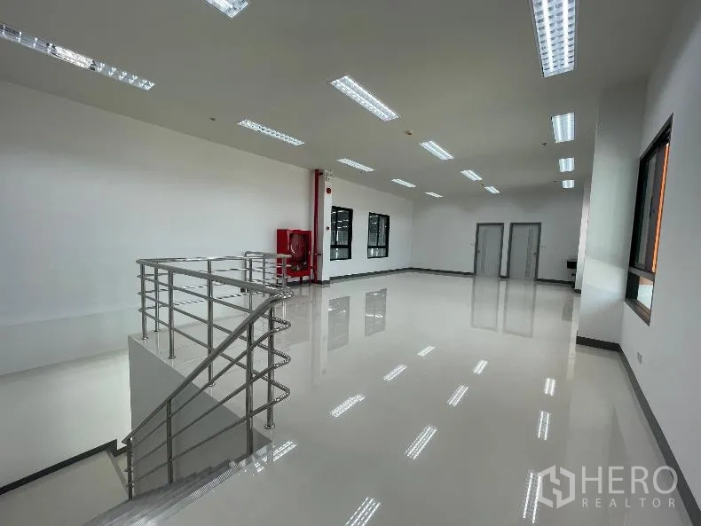 Factory for rent in Bang Sao Thong, Samut Prakan - Bright office space with polished floors, windows, fluorescent lighting, and a stainless stair railing.