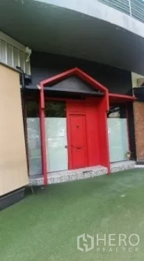 零售空间 出租在Khlong Toei, Bangkok - 外部入口设红色山墙门廊与磨砂玻璃，前方为人造草坪。