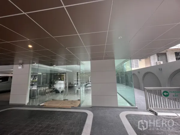 Retail Space for rent in Watthana, Bangkok - Corner retail space beneath covered drop-off with floor-to-ceiling windows and parking access.