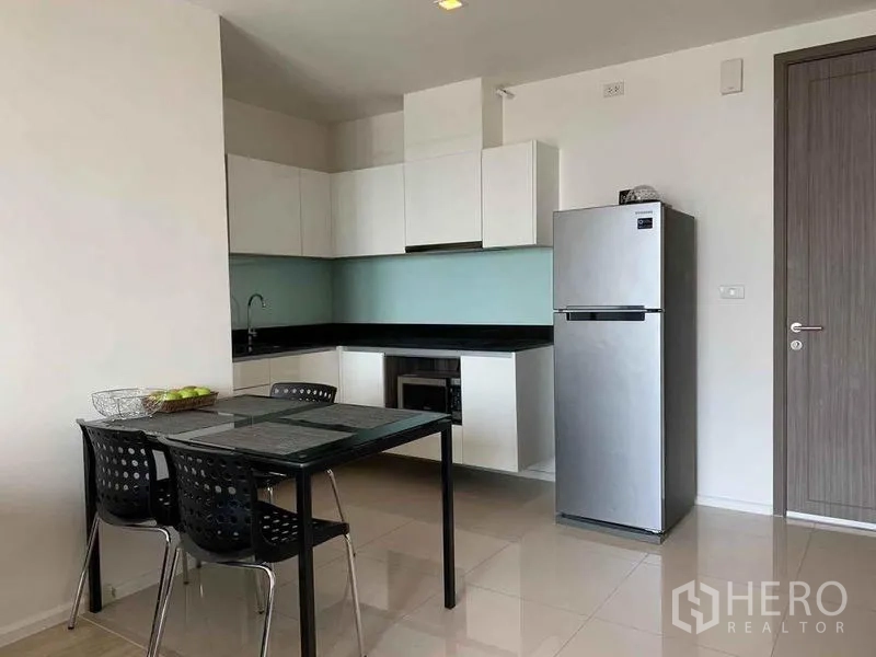 公寓 出租或出售在Din Daeng, Bangkok - L形厨房，白色柜体与不锈钢冰箱。