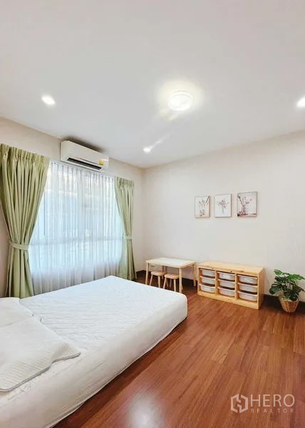 Townhouse for rent in Phra Khanong, Bangkok - Minimal guest bedroom with green curtains and wood floors.