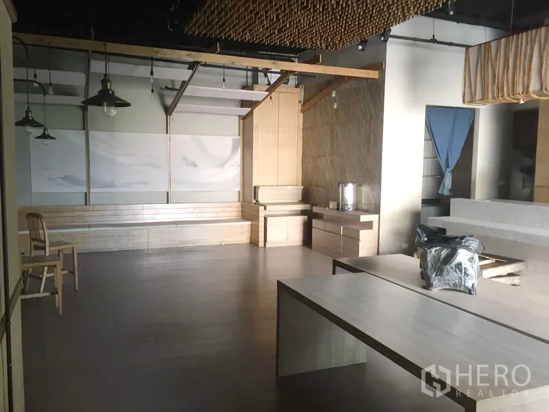 Retail Space for rent in Khlong Toei, Bangkok - Spacious open-plan shop floor with light wood benches, pendant lights, and built-in cabinetry.