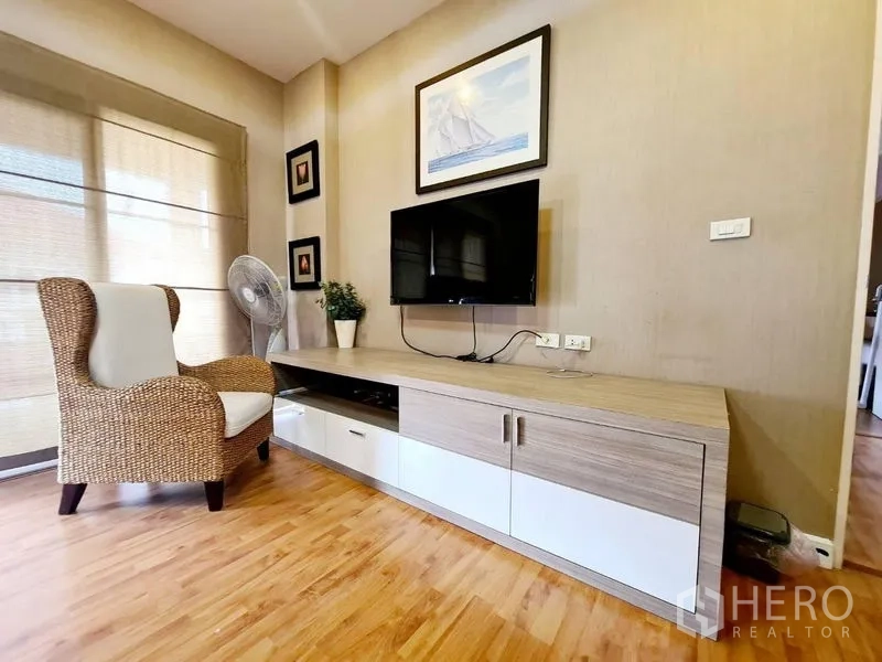 Detached House for rent in Sai Mai, Bangkok - Cozy lounge corner with wicker armchair, TV console and window blinds.