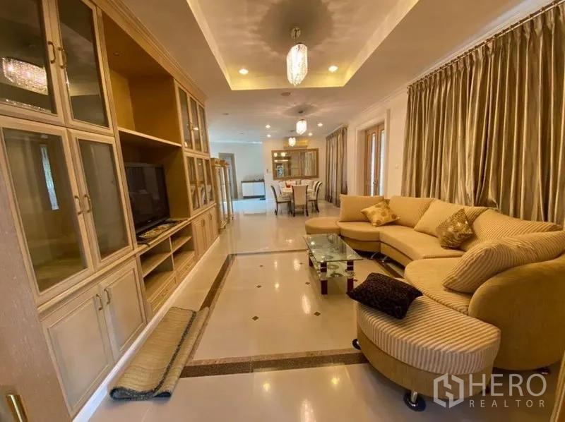 Detached House for rent in Bang Phli, Samut Prakan - Open-plan living area with L-shaped sofa, built-in media wall and ceiling lights.
