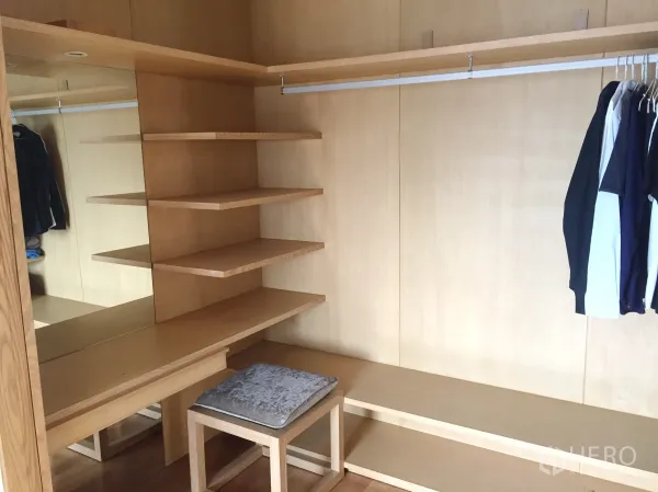 Condominium for rent in Khlong Toei, Bangkok - Spacious walk-in closet with open shelves, vanity, and hanging rail in a light wood finish.