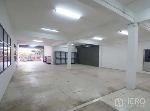 货栈 出租在Bang Kapi, Bangkok - 开放式仓库区，白色立柱、日光灯、混凝土地面及装卸卷闸门。