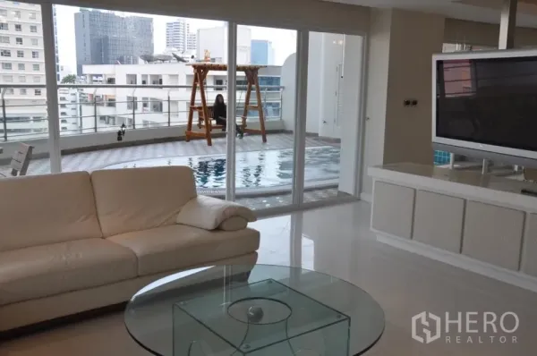 Condominium for rent in Khlong Toei, Bangkok - Open‑plan lounge facing sliding doors to a large private terrace with swimming pool and skyline outlook.