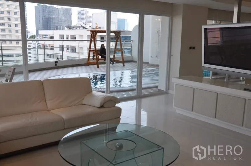 Condominium for rent in Khlong Toei, Bangkok - Open‑plan lounge facing sliding doors to a large private terrace with swimming pool and skyline outlook.