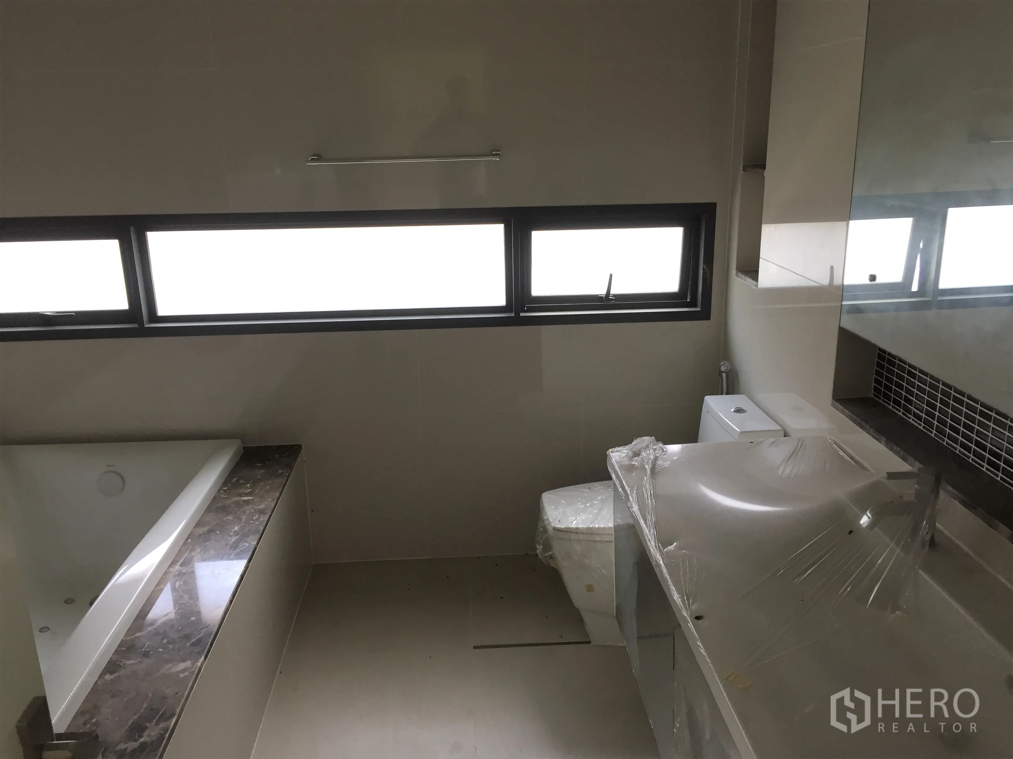 独立式住宅 出租或出售在Prawet, Bangkok - 浴室配浴缸、长台面洗手台与横向窗户。