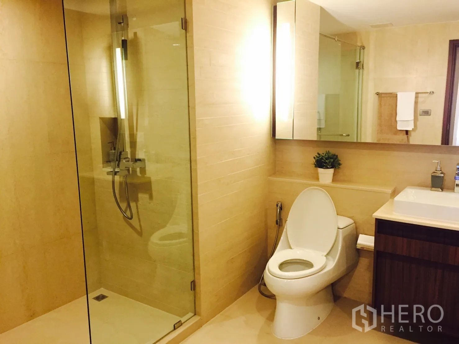 Condominium for rent or sale in Sathon, Bangkok - Contemporary bathroom featuring a glass-enclosed shower, large mirror, and toilet.