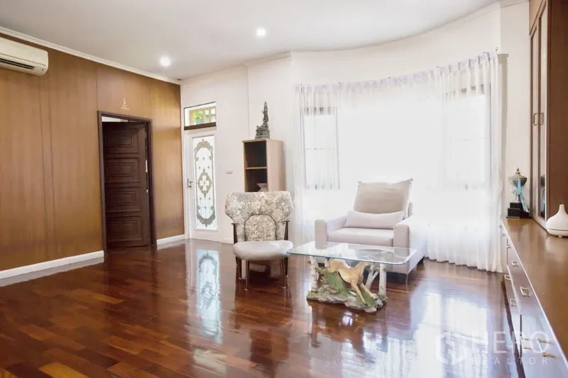 Detached House for sale in Lat Krabang, Bangkok - Upstairs sitting room with bay window, armchairs, glass table and wooden floors.