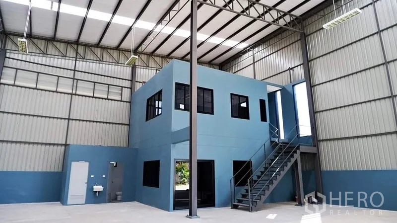 Warehouse for rent in Bueng Kum, Bangkok - High-clear warehouse interior with a two-story office box and open floor area.