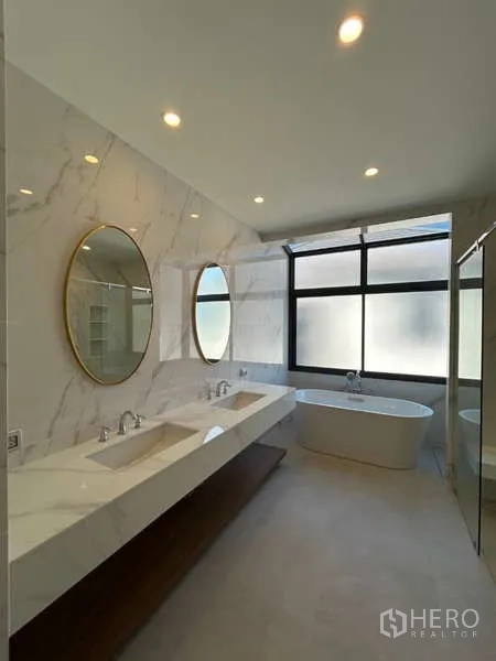 Detached House for sale in Bang Kapi, Bangkok - Luxurious master bathroom with double vanity, round mirrors and freestanding tub.