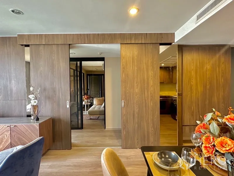 Condominium for rent in Pathum Wan, Bangkok - Sliding wooden doors revealing a bedroom beyond with warm lighting and storage.