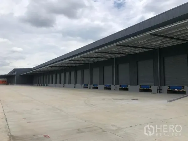 Factory for rent in Wang Noi, Phra Nakhon Si Ayutthaya - Long covered loading dock with multiple roller shutter doors and a wide truck apron.